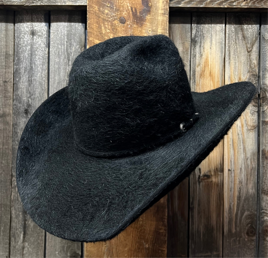 Black rough cowboy hat leaning against a wooden fence