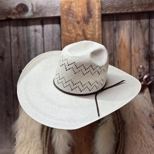White cowboy hat with decorative band on a wooden background
