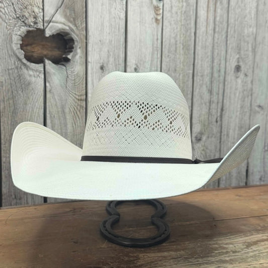 A white cowboy hat with a 5-inch brim, leather sweatband, and a black cord ribbon band, displayed on a stand against a wooden background.