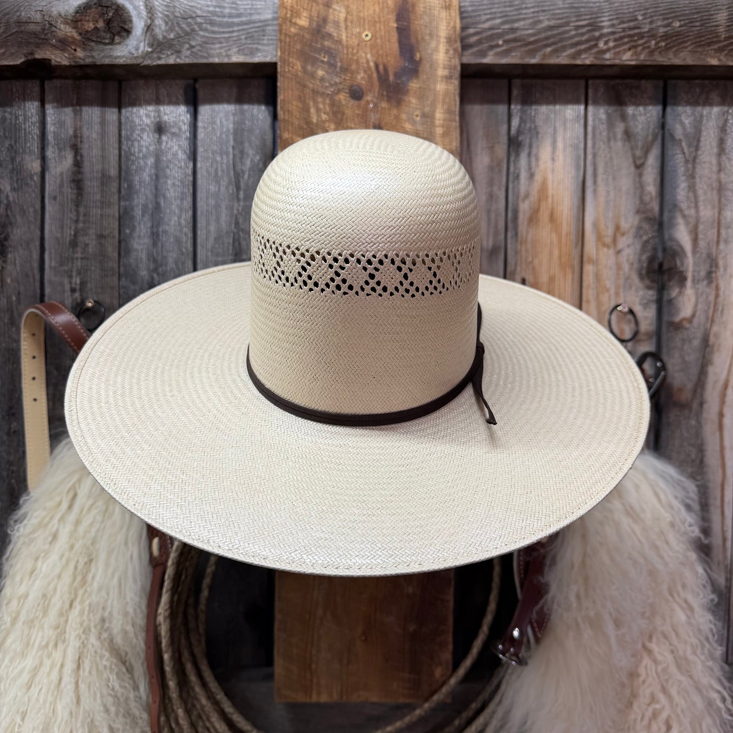 Beige straw hat with black band on a wooden background