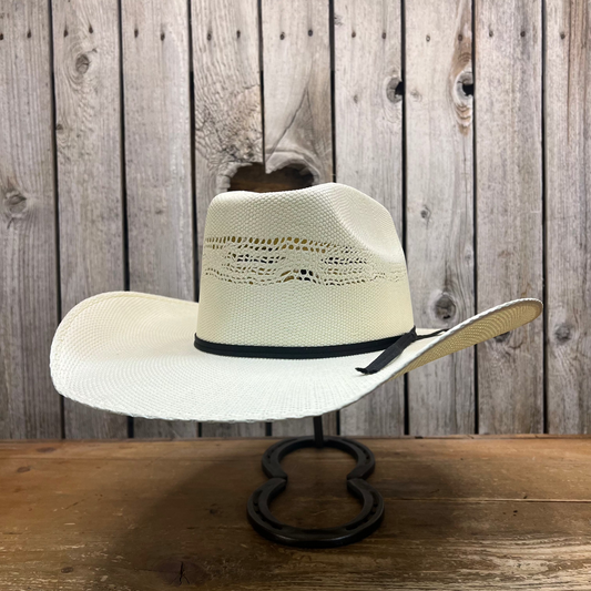 White straw cowboy hat on a wooden stand against a rustic wooden wall.