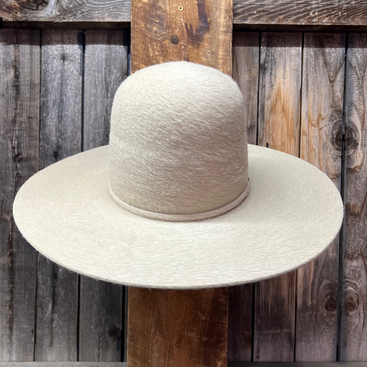 Furry White straw hat on a wooden stand against a wooden wall