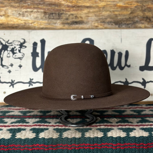 A whiskey brown Rodeo King cowboy hat with a 4 1/2 inch brim displayed on a stand, featuring a whiskey buckle on the band.