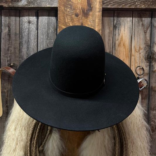 A black wide-brim fedora hat displayed on a rustic wooden stand with a white fur collar, rope, and a weathered wood plank background.