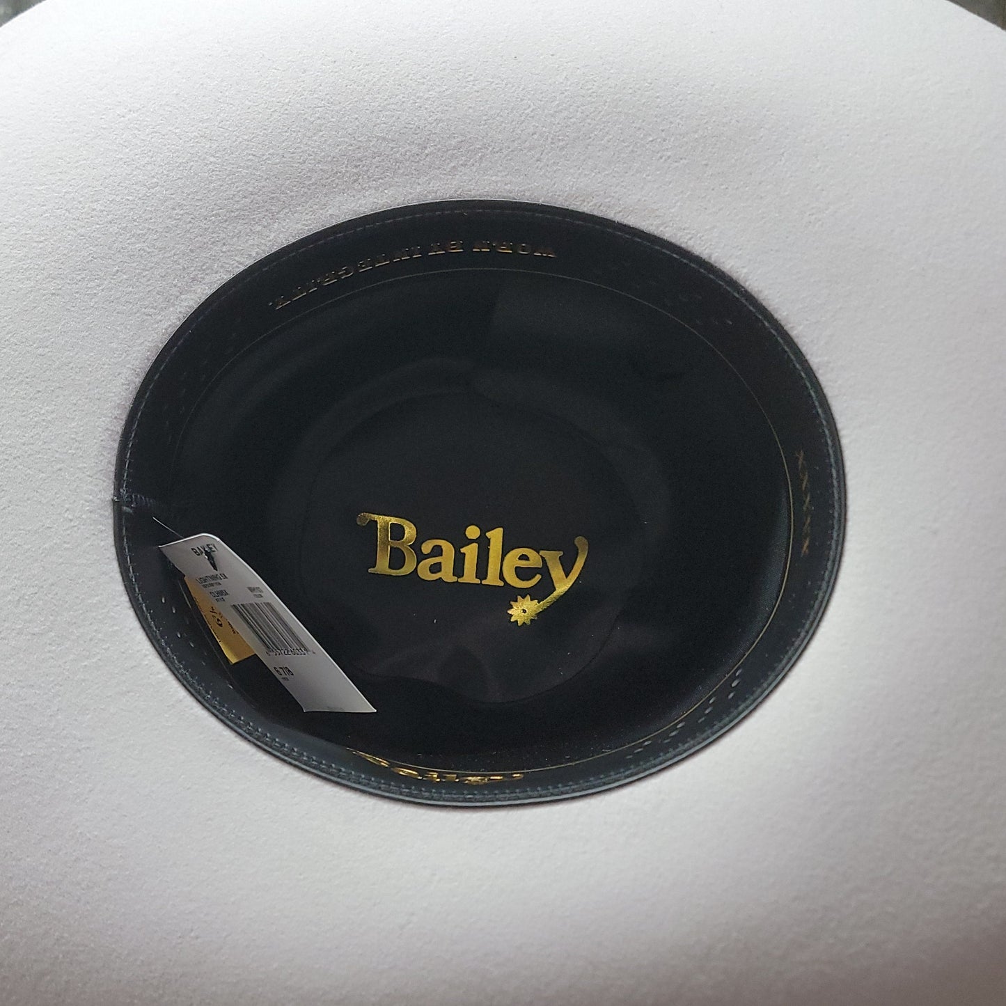 White cowboy hat with 'Bailey' logo on a wooden surface