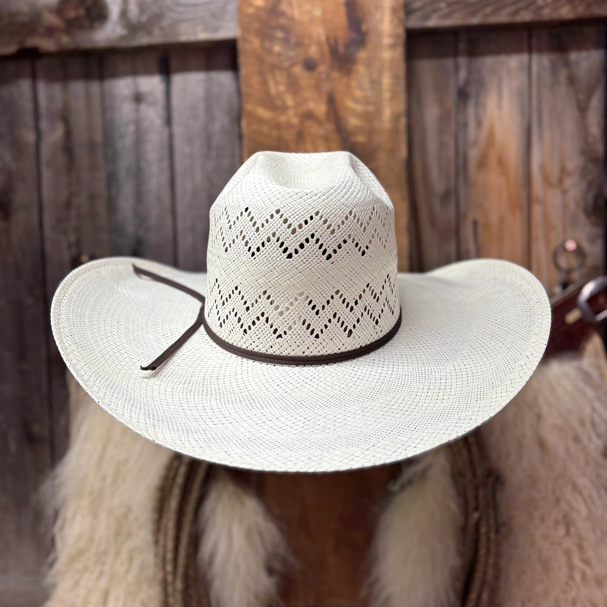 White straw hat with brown band on a wooden background