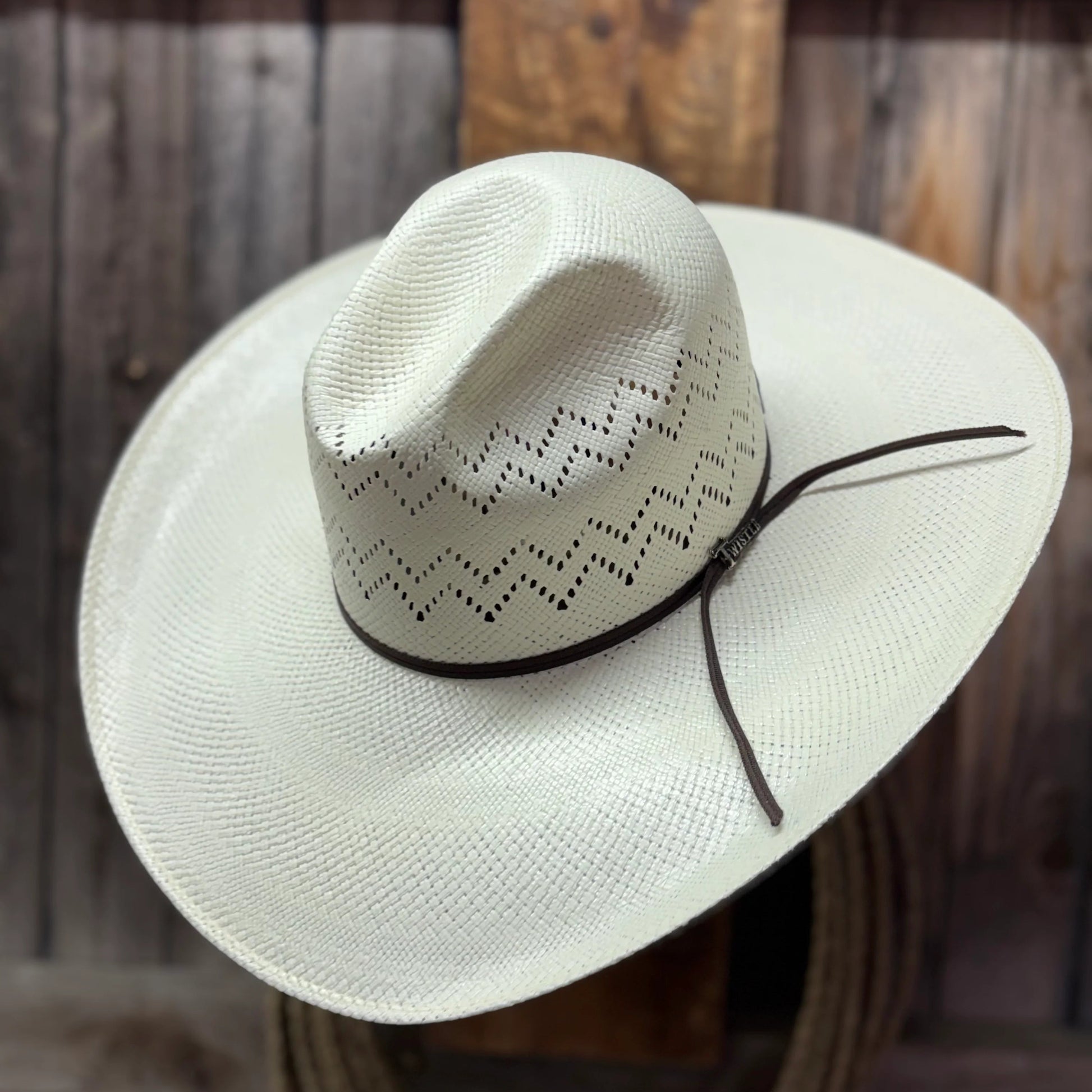 White cowboy hat with a black band on a wooden surface