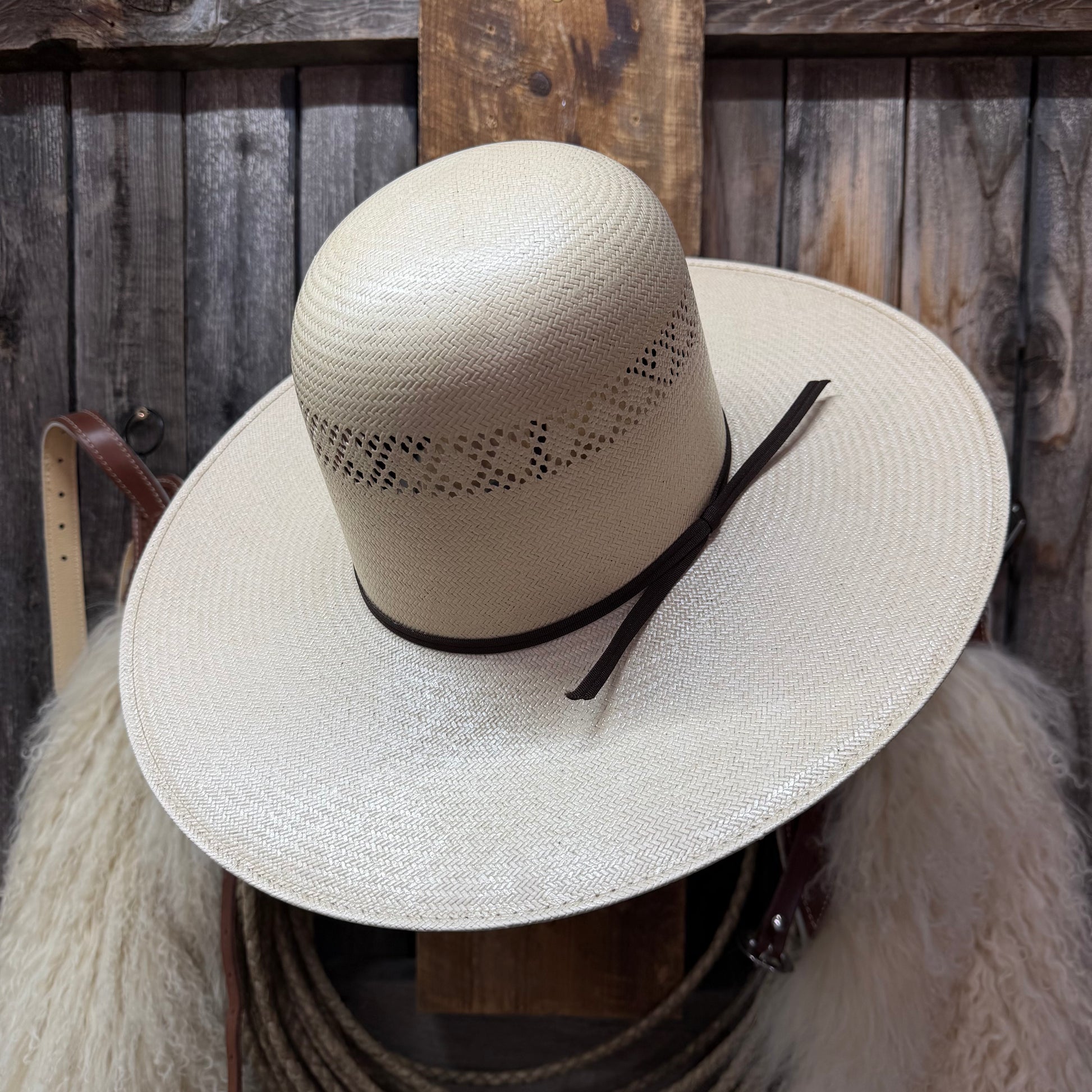Beige straw hat with a black band on a wooden background
