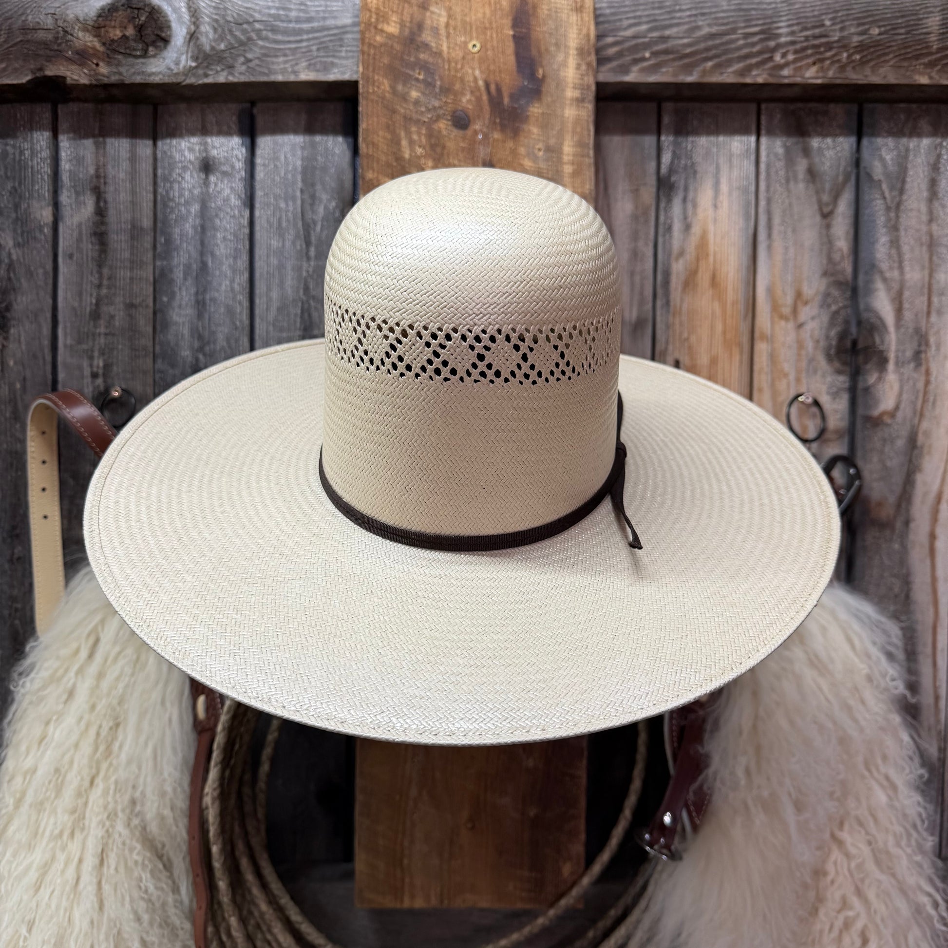 Beige straw hat with black band on a wooden background