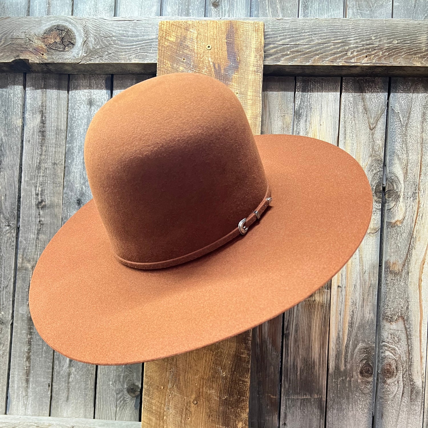 Brown hat on a wooden stand against a rustic wooden wall