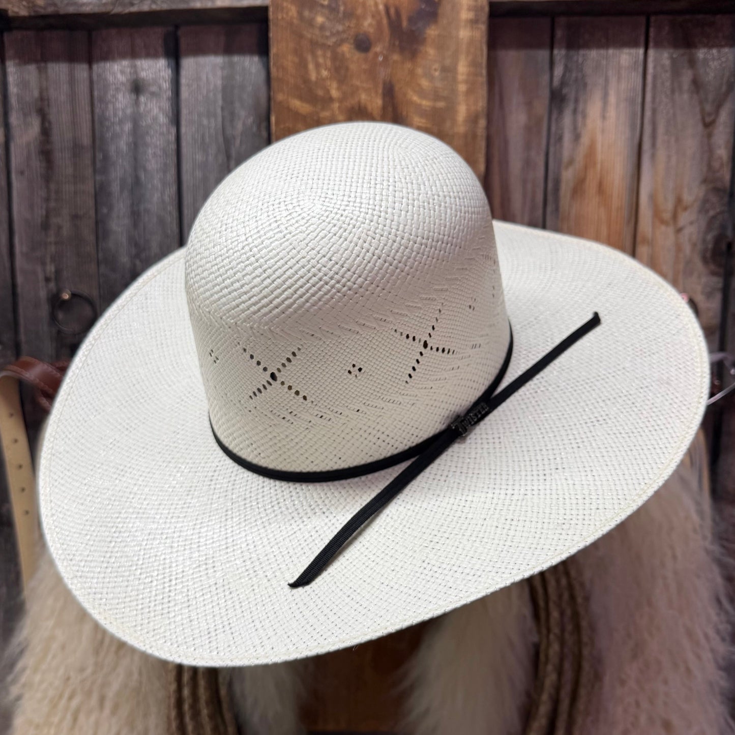 White straw hat with black band on a wooden surface