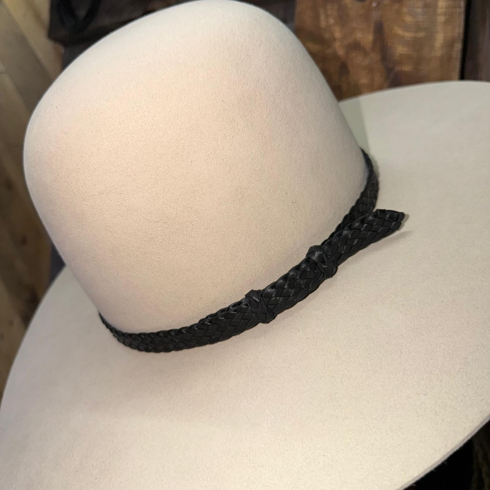 White wide-brimmed hat with a black braided band on a mannequin head.