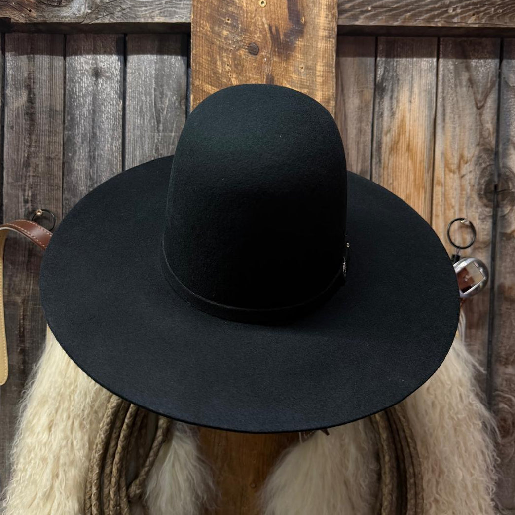 A black wide-brim fedora hat displayed on a rustic wooden stand with a white fur collar, rope, and a weathered wood plank background.
