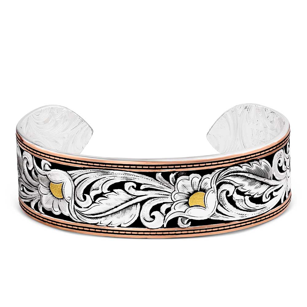 A silver cuff bracelet featuring an engraved floral scroll pattern in black, white, and gold, with a polished rose gold-toned edge.