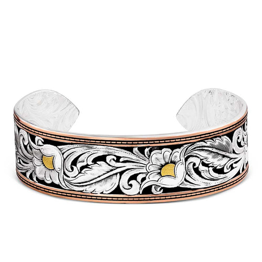 A silver cuff bracelet featuring an engraved floral scroll pattern in black, white, and gold, with a polished rose gold-toned edge.