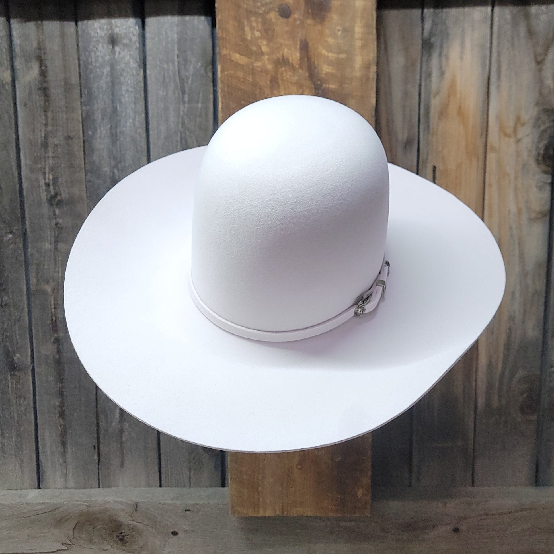 White wide-brimmed hat on a wooden surface with a wooden panel background